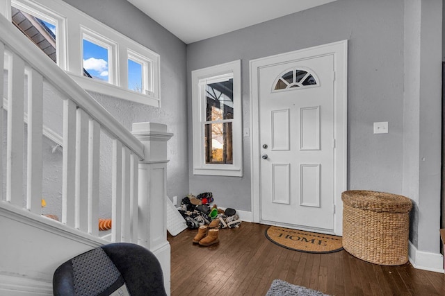 foyer entrance featuring wood-type flooring, baseboards, and stairway