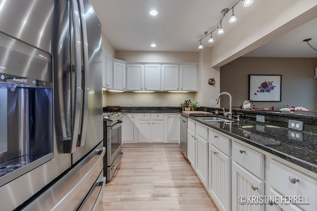 kitchen with white cabinetry, appliances with stainless steel finishes, a sink, and light wood-style flooring