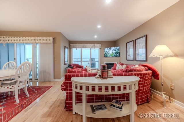living room featuring recessed lighting, baseboards, and light wood-type flooring