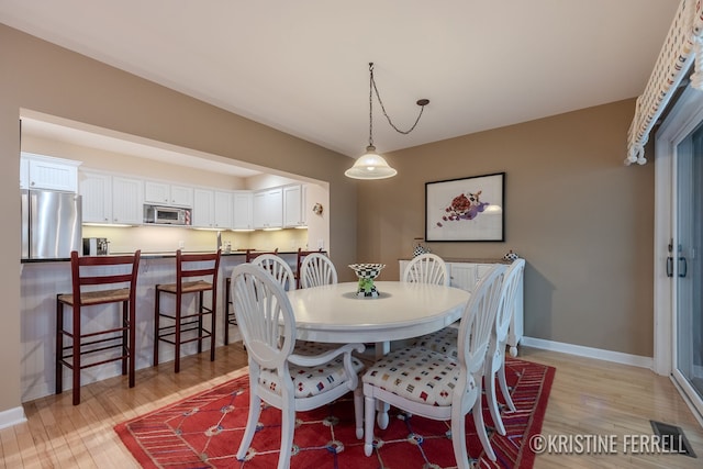 dining area with baseboards and light wood-style flooring