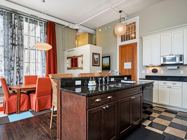 800-204 Cottageview Dr, Traverse City, MI 49684 - kitchen featuring a sink, a kitchen breakfast bar, stainless steel microwave, a towering ceiling, and a center island with sink