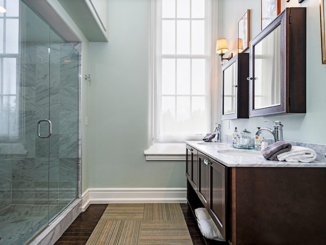 800-204 Cottageview Dr, Traverse City, MI 49684 - full bathroom featuring double vanity, wood finished floors, baseboards, a sink, and a stall shower