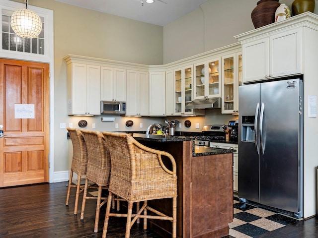 800-204 Cottageview Dr, Traverse City, MI 49684 - kitchen featuring a kitchen island, a breakfast bar area, under cabinet range hood, dark floors, and appliances with stainless steel finishes