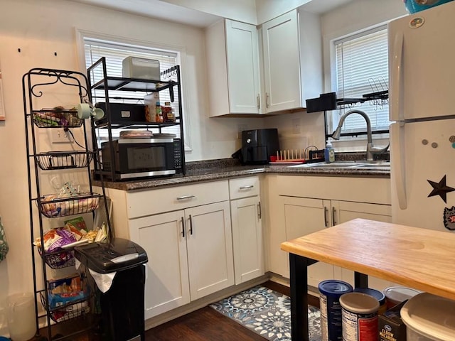 kitchen featuring freestanding refrigerator, stainless steel microwave, a wealth of natural light, and a sink
