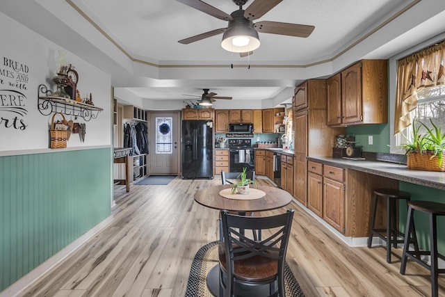 220 Nottingham Dr, Brooklyn, MI 49230 - kitchen with brown cabinets, ceiling fan, dark countertops, light wood-style flooring, and black appliances