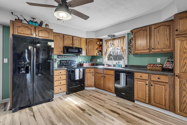 220 Nottingham Dr, Brooklyn, MI 49230 - kitchen featuring dark countertops, a sink, brown cabinetry, light wood-type flooring, and black appliances