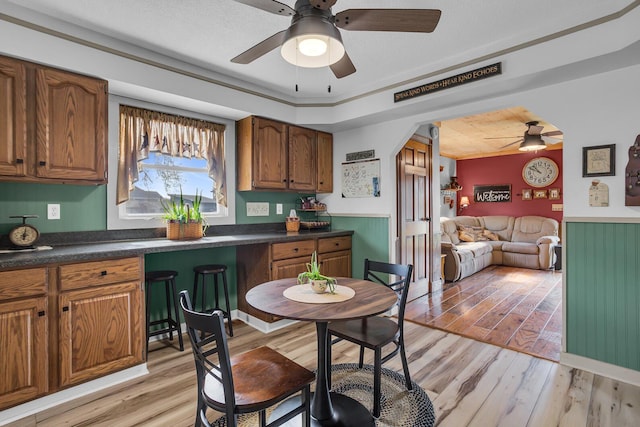 220 Nottingham Dr, Brooklyn, MI 49230 - kitchen featuring brown cabinetry, a ceiling fan, light wood finished floors, and dark countertops