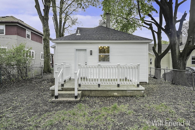 back of house with fence, a shingled roof, and a deck