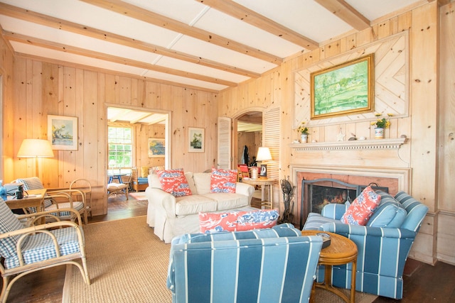 living area featuring wooden walls, arched walkways, a warm lit fireplace, and wood finished floors