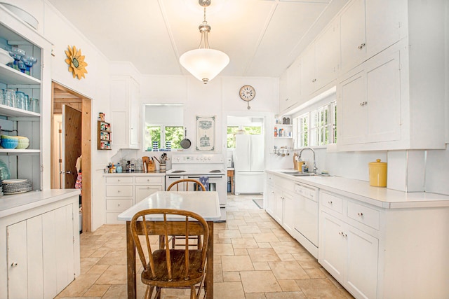kitchen featuring white appliances, white cabinetry, stone finish floor, and a sink