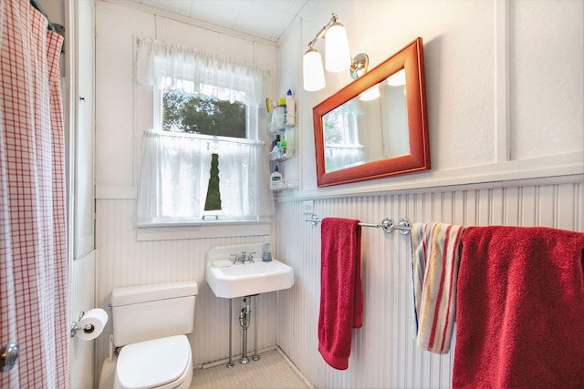 full bath featuring a sink, wainscoting, toilet, and a shower with curtain