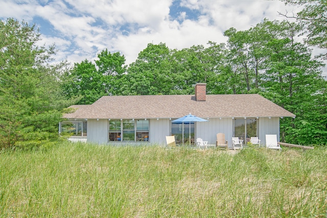 back of property featuring a shingled roof and a chimney
