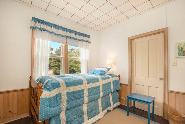 bedroom with wood walls and a wainscoted wall