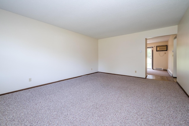 carpeted spare room featuring an AC wall unit, baseboards, and baseboard heating