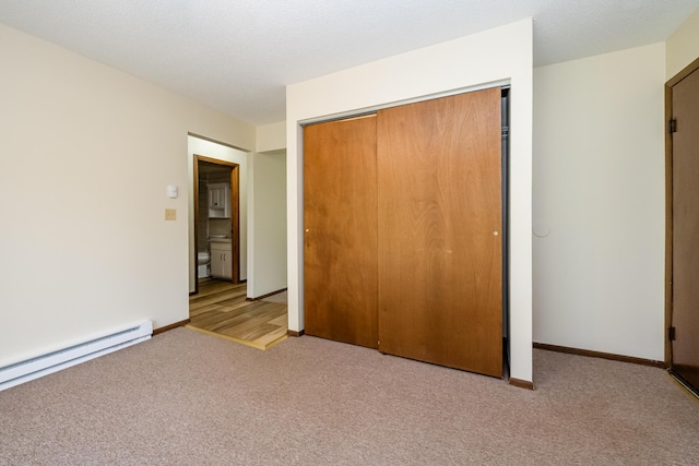 unfurnished bedroom featuring a closet, carpet, baseboards, and baseboard heating