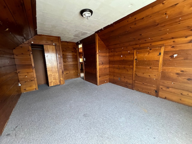 bonus room featuring carpet floors, lofted ceiling, and wooden walls