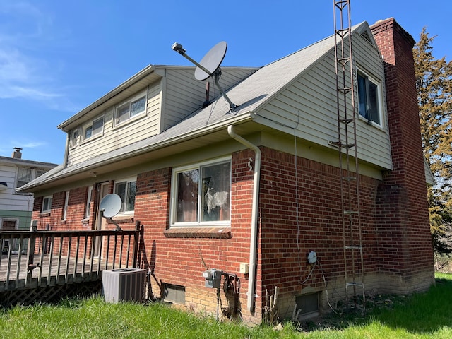 view of side of property featuring brick siding, a wooden deck, and central air condition unit