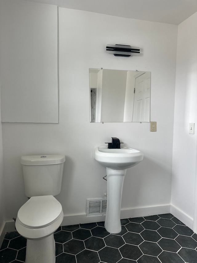 half bath featuring baseboards, a sink, and toilet