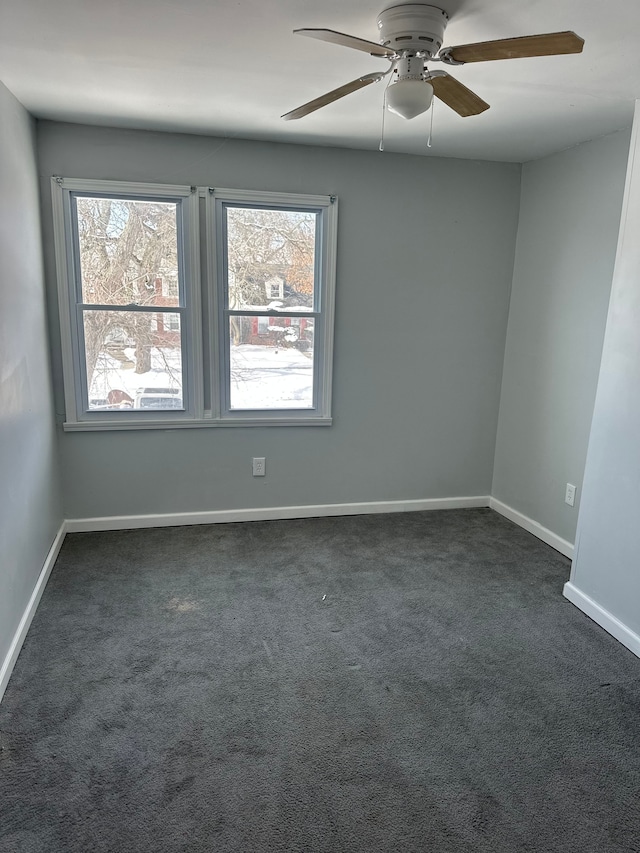empty room with dark carpet, a ceiling fan, and baseboards