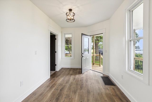 doorway with baseboards, visible vents, an inviting chandelier, and dark wood-type flooring