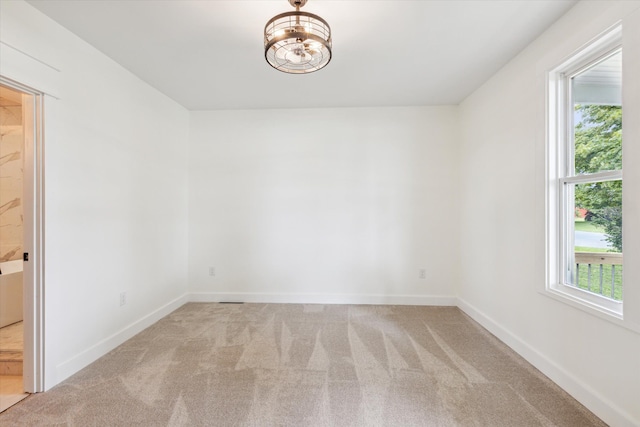 carpeted empty room with baseboards and a notable chandelier