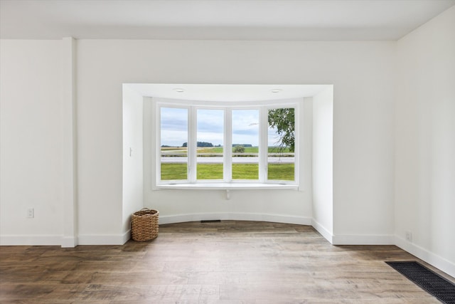 unfurnished room featuring baseboards, wood finished floors, and visible vents