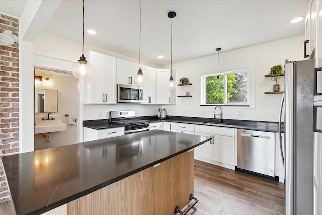 kitchen with open shelves, dark wood-style flooring, dark countertops, a sink, and appliances with stainless steel finishes