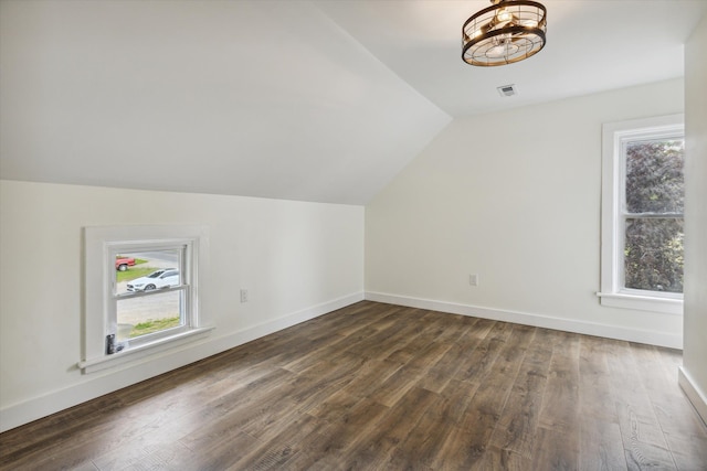 additional living space with visible vents, lofted ceiling, dark wood-style floors, and a healthy amount of sunlight