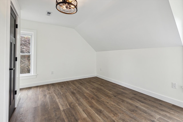 bonus room featuring visible vents, an inviting chandelier, lofted ceiling, baseboards, and dark wood finished floors