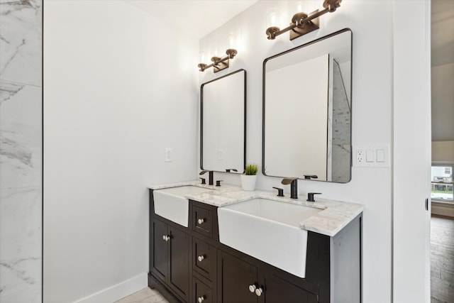 bathroom featuring a sink, baseboards, double vanity, and marble finish floor