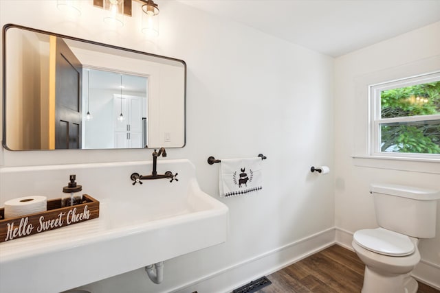 bathroom featuring a sink, toilet, baseboards, wood finished floors, and visible vents