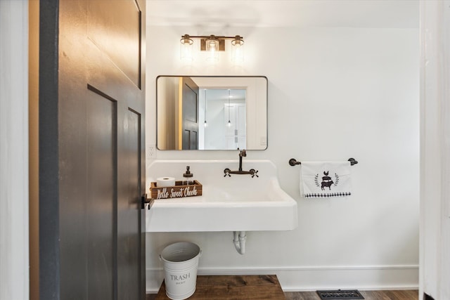 bathroom featuring visible vents, a sink, baseboards, and wood finished floors
