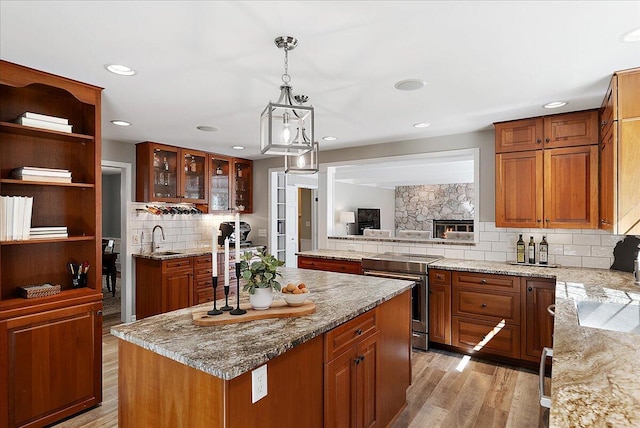kitchen featuring electric range, light stone countertops, a center island, a sink, and backsplash