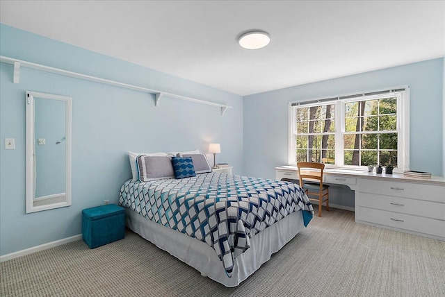 bedroom with baseboards, light carpet, and built in desk