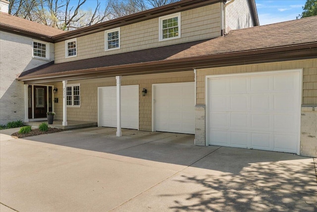 view of front facade with a garage, a shingled roof, and concrete driveway