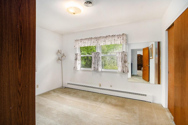 carpeted spare room featuring visible vents and baseboard heating