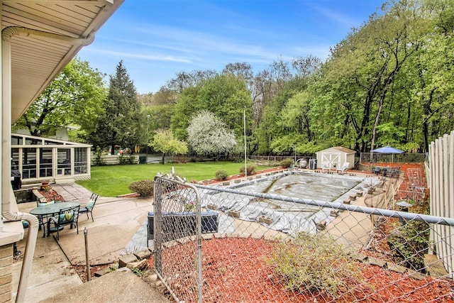 view of patio / terrace with an outdoor structure, a fenced backyard, a shed, and a sunroom