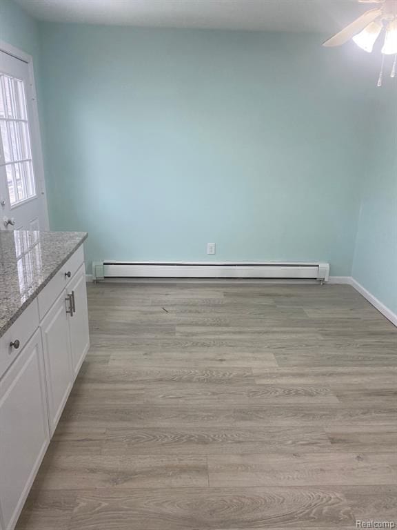 32198 Truman Rd, Rockwood, MI 48173 - unfurnished dining area with a baseboard radiator, baseboards, ceiling fan, and light wood-type flooring