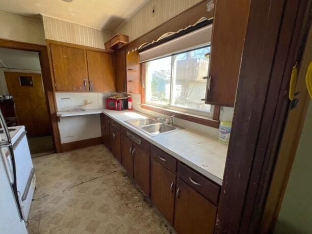 kitchen featuring light countertops, white range with electric stovetop, a sink, and light floors