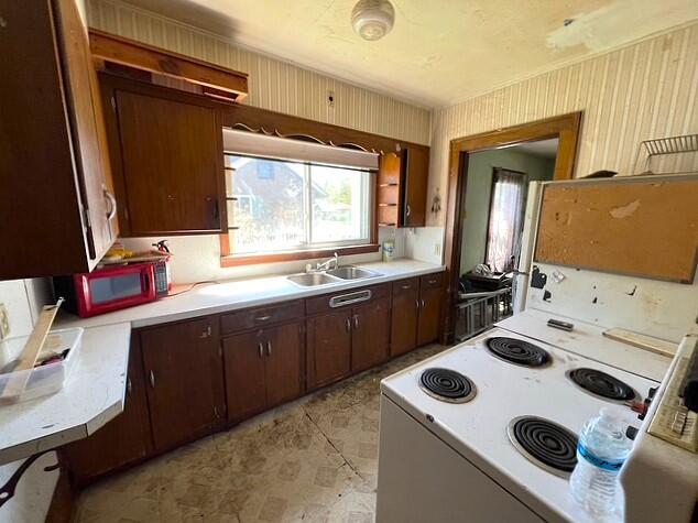 kitchen featuring crown molding, dark brown cabinets, white range with electric cooktop, light countertops, and a sink