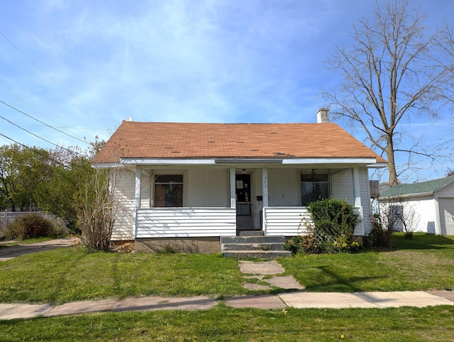 bungalow featuring a porch, a chimney, and a front lawn