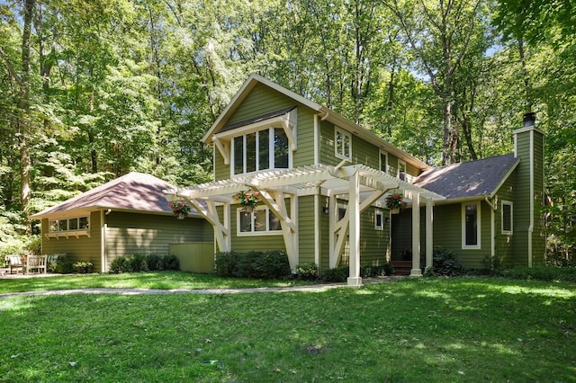 view of front facade with a pergola, a chimney, a front yard, and roof with shingles