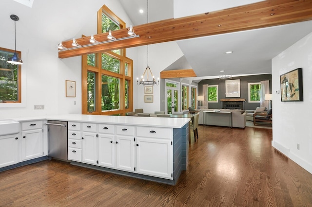 kitchen with stainless steel dishwasher, a peninsula, white cabinets, and dark wood-style floors