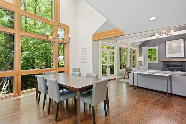 dining space with lofted ceiling with beams, french doors, wood finished floors, and a notable chandelier