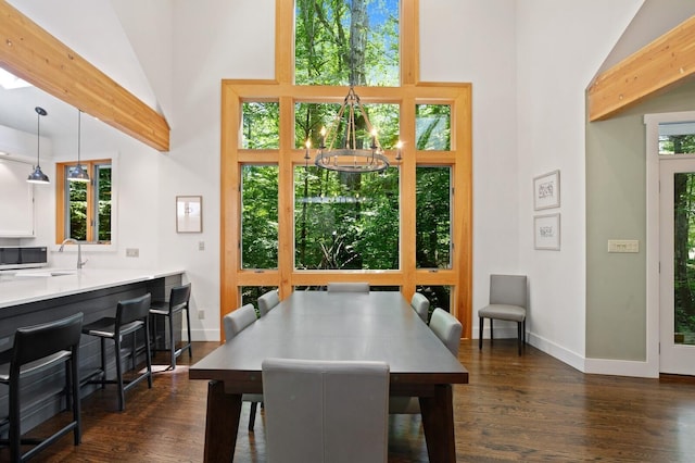 dining room featuring an inviting chandelier, baseboards, dark wood-style flooring, and high vaulted ceiling