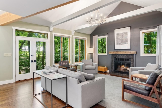 living room with dark wood-style flooring, lofted ceiling with beams, a chandelier, a glass covered fireplace, and french doors