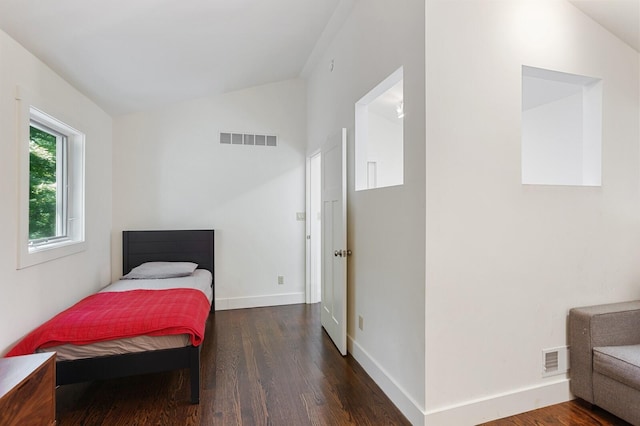 bedroom with baseboards, visible vents, wood finished floors, and lofted ceiling