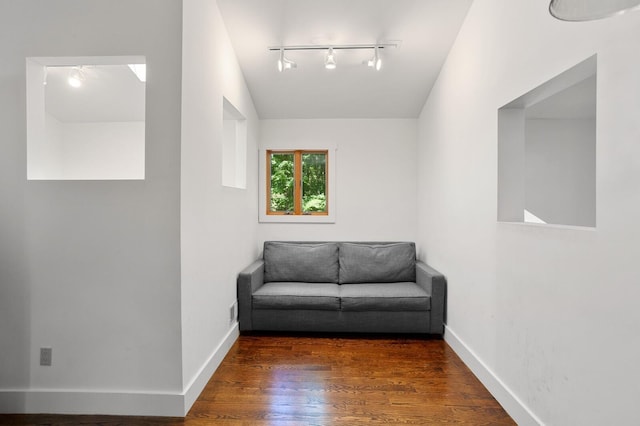 living area featuring track lighting, baseboards, and wood finished floors