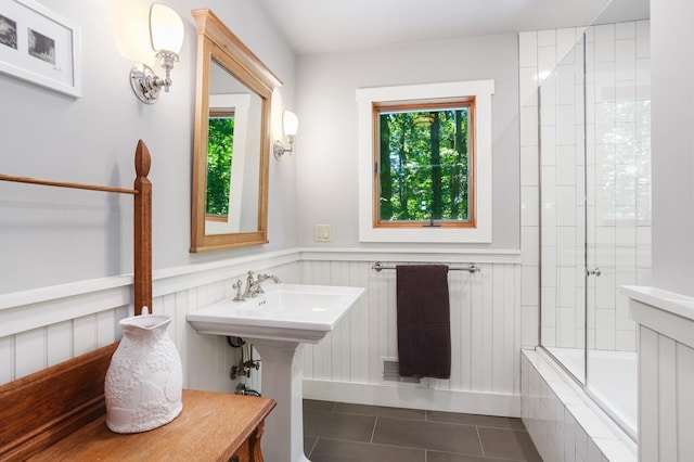 bathroom featuring tile patterned flooring, wainscoting, and tiled shower / bath
