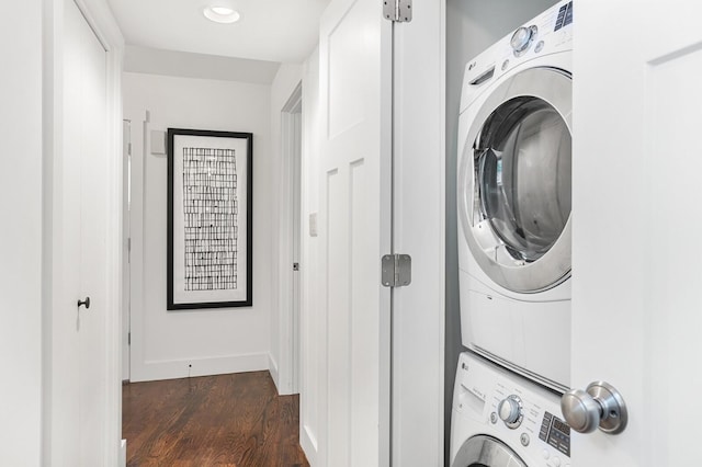 laundry area featuring laundry area, dark wood finished floors, baseboards, and stacked washer / dryer